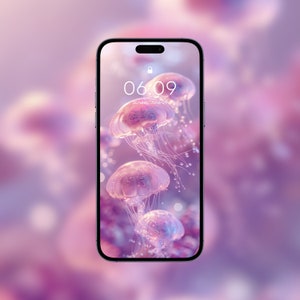 Peut inclure: Un smartphone avec un fond rose et violet présentant un gros plan de plusieurs méduses. L'heure affichée à l'écran est 06:09 et la date est dimanche 09 juin.