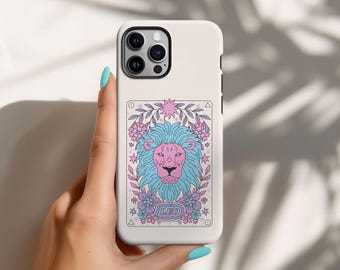 Puede incluir: Carcasa de teléfono blanca con una ilustración rosa y azul de una cabeza de león con flores y estrellas. El texto "LEO" está impreso debajo de la cabeza del león.