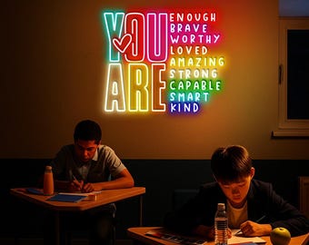 Op de afbeelding: Een veelkleurig neonbord met de woorden "YOU ARE" en een hartsymbool. Daaronder staan positieve affirmaties: ENOUGH, BRAVE, WORTHY, LOVED, AMAZING, STRONG, CAPABLE, SMART, KIND. Twee leerlingen zitten aan bureaus.
