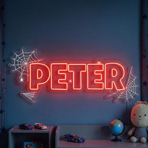 Puede incluir: Un letrero de neón rojo personalizado que muestra el nombre PETER en letras mayúsculas negritas. El letrero presenta diseños de telarañas de neón blanco en los lados, con pequeñas arañas integradas en el texto rojo brillante y los patrones.