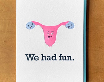 May include: A pink uterus with a sad face and two blue eyes with X's for pupils. The uterus is holding two blue circles with X's for pupils. The text "We had fun." is below the uterus.