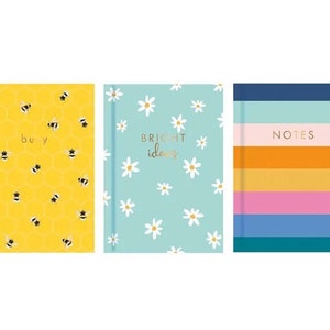 May include: Three different notebooks with colorful designs. The first notebook has a yellow cover with a honeycomb pattern and black bees. The text "busy" is printed in gold on the cover. The second notebook has a light blue cover with a white daisy pattern. The text "bright ideas" is printed in gold on the cover. The third notebook has a blue, pink, yellow, and orange striped cover. The text "NOTES" is printed in white on the cover.