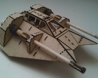 May include: A wooden model of a spacecraft with two long, cylindrical cannons extending from the front. The model is constructed from light brown wood with dark lines outlining the design, and features a cockpit area.