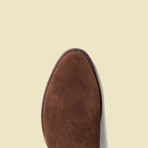 May include: Close-up of the top of a brown suede boot.