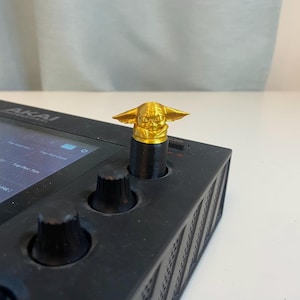 May include: A black music production controller with a gold knob featuring a character from the Star Wars franchise. The knob is labeled "AKAI PROFESSIONAL".