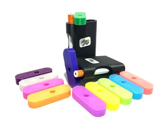 May include: A black and purple storage case with a green lid and a small orange and white filter. The case is open and there are seven colorful silicone filter tips in front of it. The case has the text "My Doob" on the side.