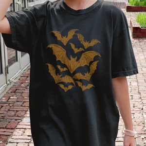 May include: A black t-shirt with a vintage-style graphic of brown bats flying in a cluster.