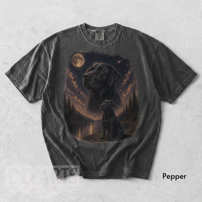Puede incluir: Camiseta gris oscuro con una ilustraci&oacute;n detallada de un Labrador Retriever negro bajo un cielo estrellado con luna llena. El dise&ntilde;o incluye un retrato m&aacute;s grande y una imagen m&aacute;s peque&ntilde;a del perro cerca de un lago y &aacute;rboles.