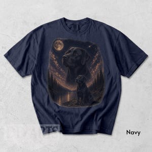 Puede incluir: Camiseta azul marino con una ilustraci&oacute;n detallada de un Labrador Retriever negro bajo un cielo estrellado con luna llena. El dise&ntilde;o incluye un perro m&aacute;s grande y un cachorro m&aacute;s peque&ntilde;o, con un lago y &aacute;rboles en el fondo. La palabra "Navy" est&aacute; impresa en la parte inferior.