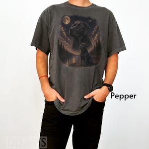 Puede incluir: Camiseta gris oscuro con un gr&aacute;fico de un Labrador Retriever negro bajo la luna llena. El dise&ntilde;o incluye una escena de bosque y lago. La palabra "Pepper" est&aacute; impresa en el lado derecho de la imagen.