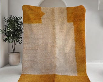 May include: A large, rectangular rug with a white center and a mustard yellow border. The rug has a fringe around the edges.