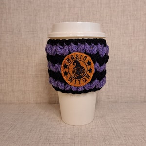 May include: Purple and black crocheted coffee cup cozy with a brown embroidered patch that says "Basic Witch" with a witch silhouette and stars.