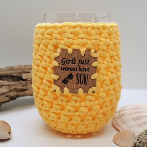 May include: Yellow crocheted wine glass cozy with a cork tag that reads "Girls just wanna have SUN" and sunglasses graphic.