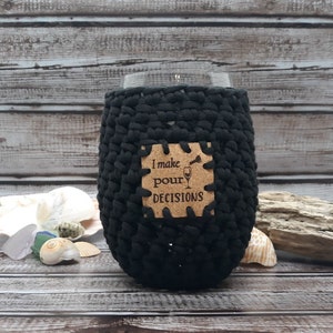 May include: Black crocheted wine glass cozy with a cork patch that reads "I make pour decisions".