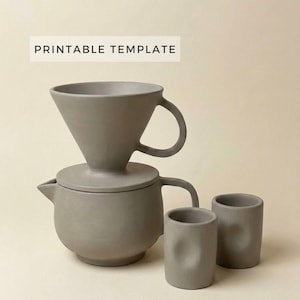 Puede incluir: Un juego de cafetera de cerámica gris mate con una tetera a juego y dos tazas pequeñas. El texto PRINTABLE TEMPLATE es visible en la parte superior. La tetera tiene un asa lateral y un pico, mientras que el filtro tiene un asa y un borde ancho.