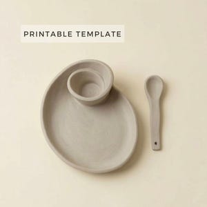 May include: A light gray ceramic serving set with a unique design. The set includes a plate with an attached bowl, and a small spoon. The text "PRINTABLE TEMPLATE" is displayed in a white rectangle above the set.