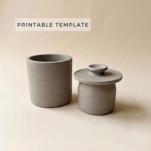 Könnte beinhalten: Zwei graue Keramikbehälter. Einer ist ein zylindrischer Becher, der andere ein kleines Glas mit Deckel. Der Text "PRINTABLE TEMPLATE" wird über den Behältern angezeigt.