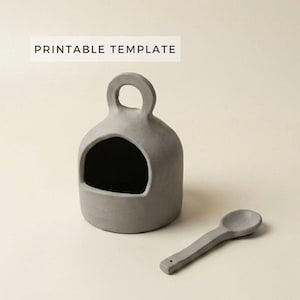 Peut inclure: Un pot à sel en céramique grise avec une cuillère assortie. Le pot à sel a une grande ouverture et une poignée. Le texte "PRINTABLE TEMPLATE" est affiché au-dessus du pot à sel.