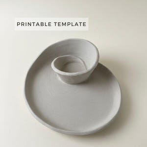May include: A gray ceramic serving dish with a unique spiral design. The dish features a small, raised bowl connected to a larger, circular plate. The text "PRINTABLE TEMPLATE" is displayed in a white rectangle at the top.