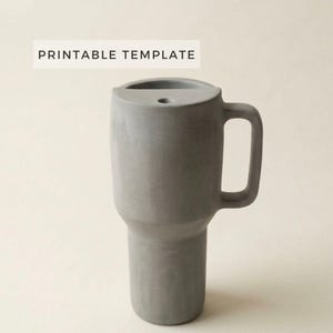 Könnte beinhalten: Ein grauer, zylindrischer Becher mit Henkel und einem kleinen Loch oben. Die Worte "PRINTABLE TEMPLATE" sind in einem weißen Rechteck über dem Becher aufgedruckt. Der Becher besteht aus einem festen, glatten Material.