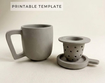 Puede incluir: Una taza de cerámica gris con un diseño de asa único y un juego de infusor de té a juego. El infusor incluye una cesta perforada y una bandeja pequeña. El texto "PRINTABLE TEMPLATE" se muestra encima de la taza.