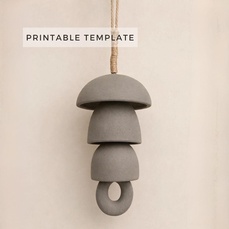 Peut inclure: Un mobile suspendu gris compos&eacute; de trois &eacute;l&eacute;ments empil&eacute;s en forme de d&ocirc;me et d'un anneau circulaire &agrave; la base, retenu par une corde beige. Le texte PRINTABLE TEMPLATE est visible en haut de l'image, indiquant un fichier de conception.