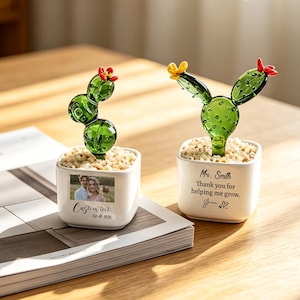 Peut inclure: Deux sculptures de cactus en verre dans des pots carrés blancs. L'un des pots porte une photo et le texte "Custom text 08-05-2020". L'autre pot porte le texte "Mr. Smith Thank you for helping me grow. You <3". Les cactus ont des fleurs rouges et jaunes.