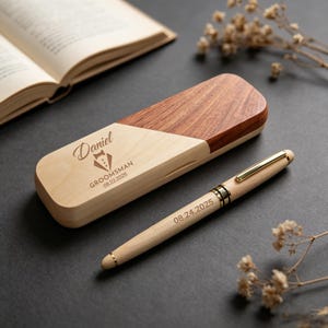 May include: A wooden pen and case set. The pen is light-colored with gold accents and engraved with a date. The case is two-toned, with a light wood and a darker wood. The case is engraved with a name, a tuxedo graphic, and a date.