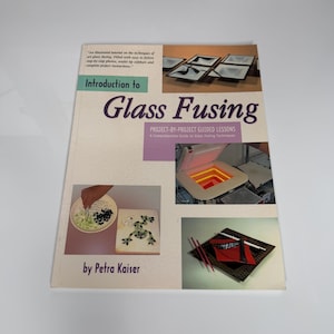 Peut inclure: Un livre intitulé "Introduction to Glass Fusing" par Petra Kaiser. La couverture présente des exemples de projets d'art du verre, notamment des assiettes en verre fusionné et un four. Le livre est un guide projet par projet sur les techniques de fusion du verre.