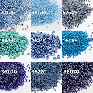 May include: A collection of seed beads in various shades of blue, teal, and purple. Each pile of beads has a unique color and a corresponding number. The beads are small and round, perfect for jewelry making and crafts.