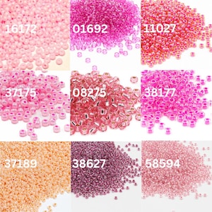 Puede incluir: Una colección de pequeñas cuentas redondas en varios tonos de rosa, melocotón y morado. Las cuentas están dispuestas en montones separados, cada uno con un color único y una etiqueta numérica correspondiente. Los colores van del rosa claro al magenta oscuro.