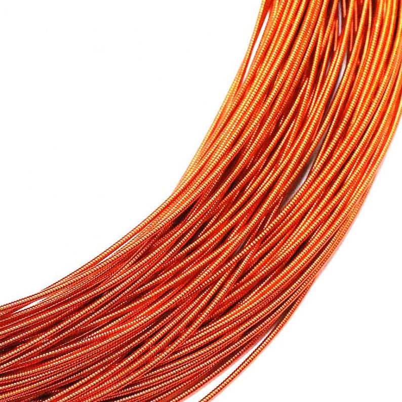 May include: A coiled length of metallic orange wire featuring a tightly wound, ribbed texture along its entire surface. The wire is arranged in a series of parallel, overlapping loops that create a dense, uniform pattern of bright copper-toned lines.