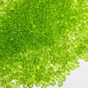 May include: A large pile of small, round, lime green glass beads. The beads are translucent and have a slight shimmer.