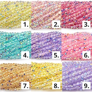 May include: A grid of nine strands of faceted glass beads in various colours, each labelled with a number from one to nine. The beads feature an iridescent finish that reflects light, showcasing shades of yellow, pink, blue, purple, and gold.