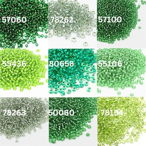 May include: A collection of seed beads in various shades of green, including emerald, lime, and seafoam. Each pile of beads has a unique product code printed on it, such as "57060" and "80658". The beads are small and cylindrical, perfect for jewelry making and crafts.
