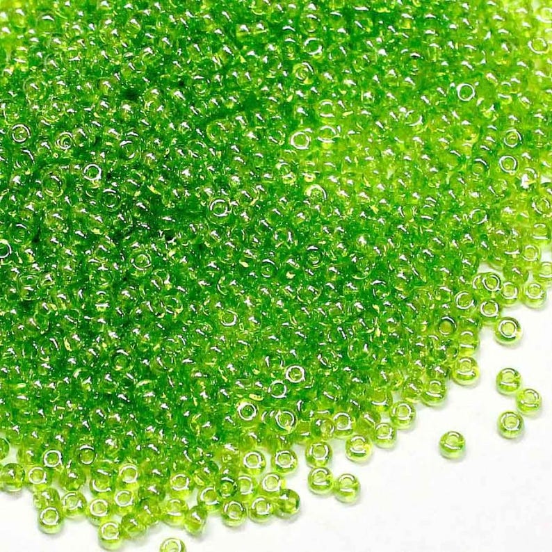 May include: A large quantity of small, round, green glass beads. The beads are translucent and have a slight shimmer.