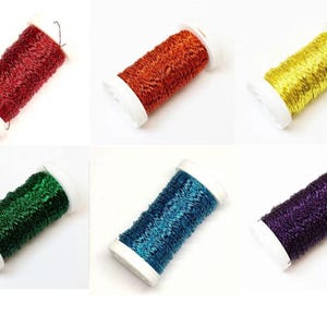 Può includere: Sei rocchetti di filo metallico in vari colori: rosso, arancione, giallo, verde, blu e viola. Ogni rocchetto ha una base e una parte superiore bianche. I fili sono ben avvolti. Ideale per progetti di artigianato e ricamo.