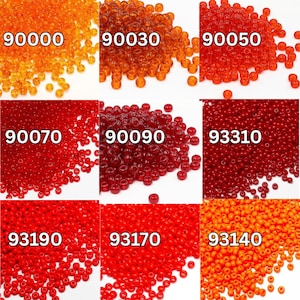 Op de afbeelding: Een verzameling kleine, ronde kralen in verschillende tinten rood en oranje. De kralen zijn gerangschikt in afzonderlijke stapels, elk gemarkeerd met een vijfcijferig nummer. De kleuren variëren van lichtoranje tot dieprood, met een glanzende afwerking.