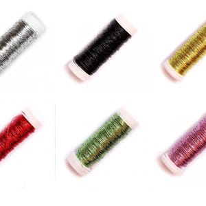 May include: Six spools of metallic thread in silver, black, gold, red, green, and pink. Each spool has white caps. The shiny threads are likely for crafts or embroidery. Measurements are not available.