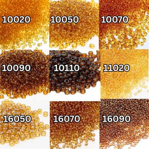 Può includere: Una collezione di piccole perline di vetro rotonde e trasparenti in varie tonalità di ambra e marrone. L'immagine è divisa in sezioni, ciascuna etichettata con un numero, che mostra i diversi colori e tonalità delle perline. Le perline sono adatte per la creazione di gioielli e artigianato.