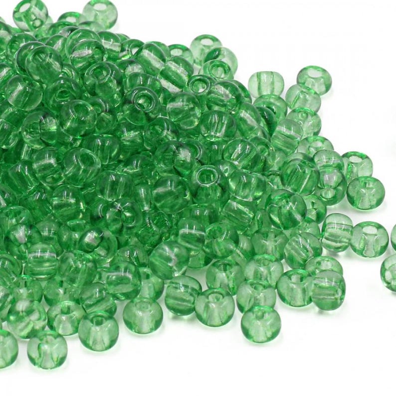 May include: A large pile of translucent green plastic beads. The beads are round and have a hole in the center.