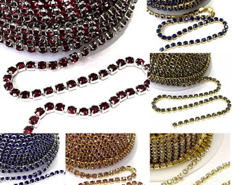 Könnte beinhalten: Sortiment an Strasskettenbesatz in verschiedenen Farben, darunter Rot, Blau, Gold, Rosa und Klar. Die Kette besteht aus kleinen, quadratischen Strasssteinen, die durch Metallglieder verbunden sind.