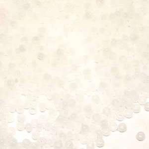 Peut inclure: Gros plan sur un tas de petites perles rondes et translucides. Les perles sont d'un blanc cassé doux et semblent être faites d'un matériau lisse et brillant. Elles sont dispersées sur le cadre, créant une surface texturée.