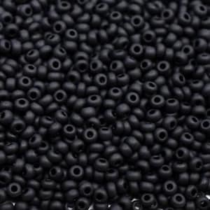 May include: A close-up of a mass of small, matte black seed beads. The beads are round with a central hole, and they are tightly packed. The beads are uniform in size and shape, creating a consistent texture. Ideal for jewellery making.