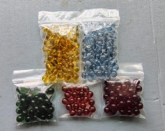May include: Five bags of colorful glass beads. The bags are clear plastic and contain different colors of beads, including yellow, blue, green, and red.