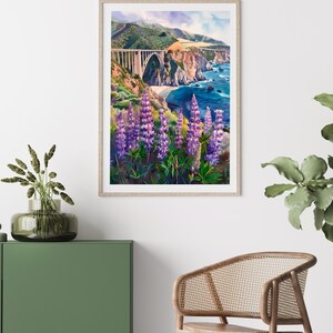 May include: A framed watercolor painting of a bridge over a body of water with a coastline in the background. The bridge is white and the water is blue. There are purple flowers in the foreground.