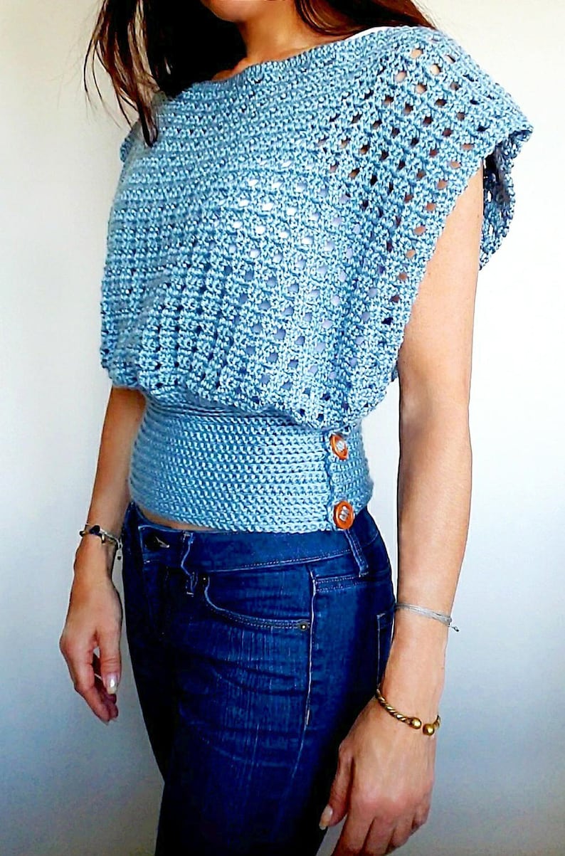 May include: A light blue crochet top with a fitted waist and short sleeves. The top has a button closure on the side.