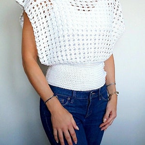 May include: White crochet top with a loose fit and a fitted band around the waist. The top has a wide, open neckline and short sleeves.