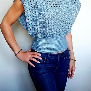 May include: A light blue crochet top with a loose, open-weave design. The top has a fitted waist and short sleeves.