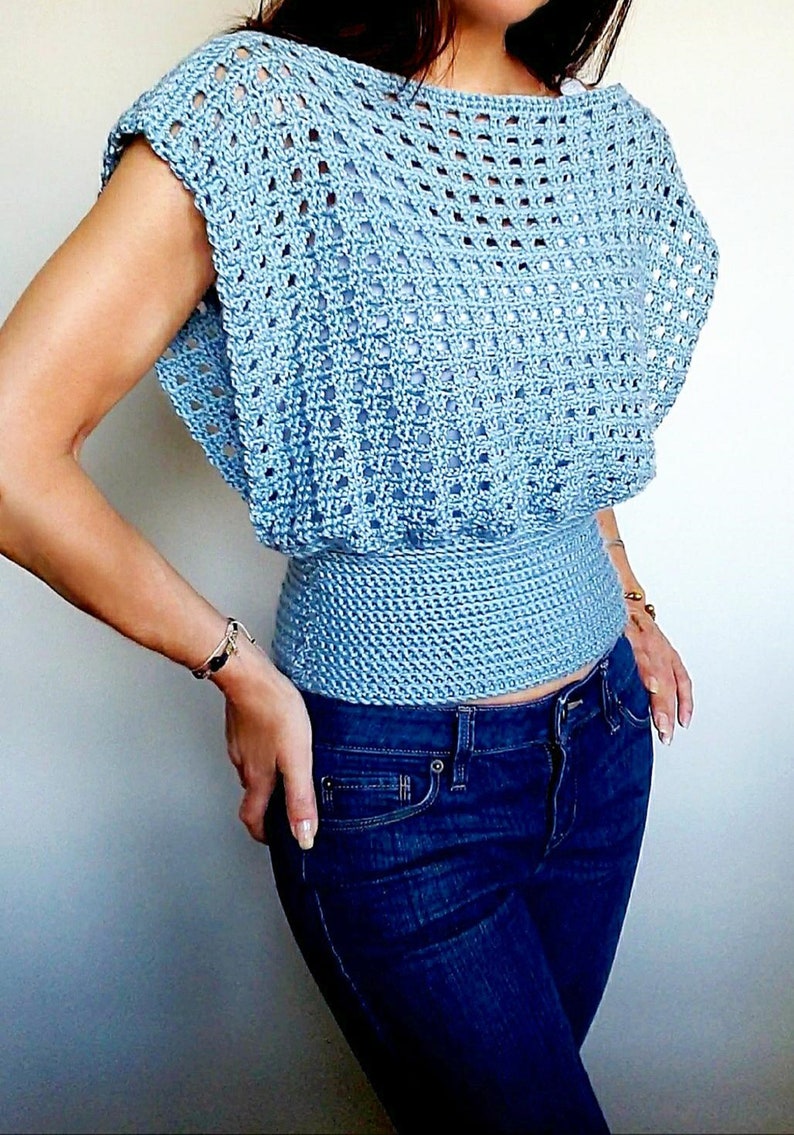 May include: A light blue crochet top with a loose fit and a fitted waist. The top has a square-shaped neckline and short sleeves.